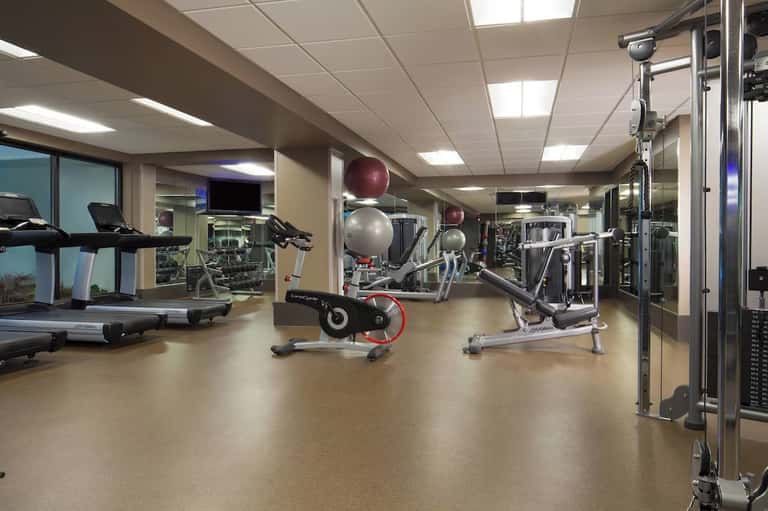 Modern fitness center with cardio equipment, exercise bikes, weight machines, and mirrors