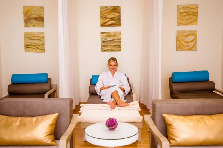Spa relaxation room with woman in white robe, modern seating, and gold wall art