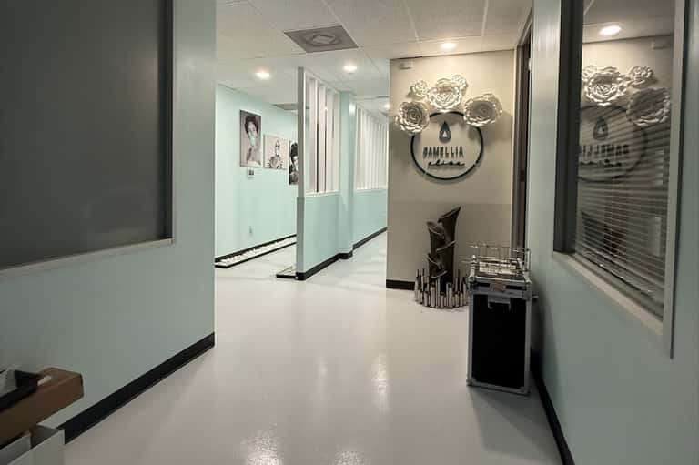 Modern salon or spa corridor with light blue and white walls, rose wall art, and professional signage