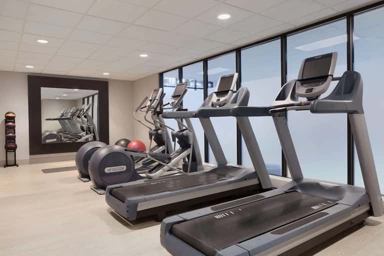Modern fitness center with treadmills, ellipticals, and large windows with ocean views