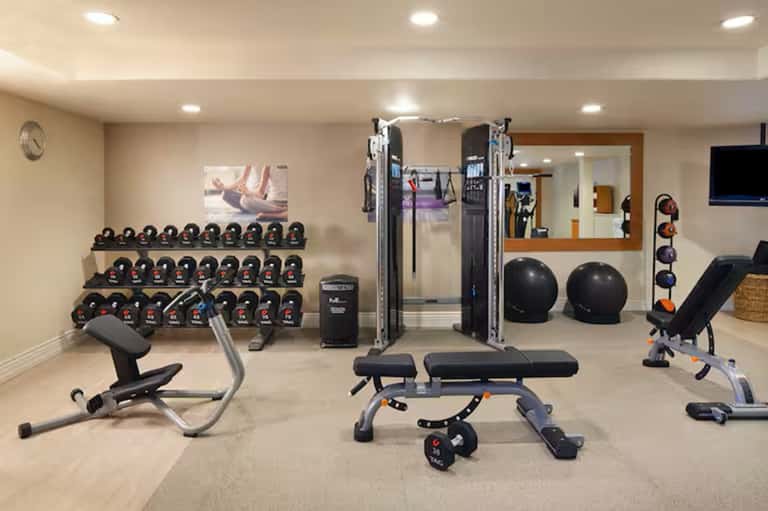 Well-equipped home gym with dumbbells, weight machines, exercise bench, and fitness equipment