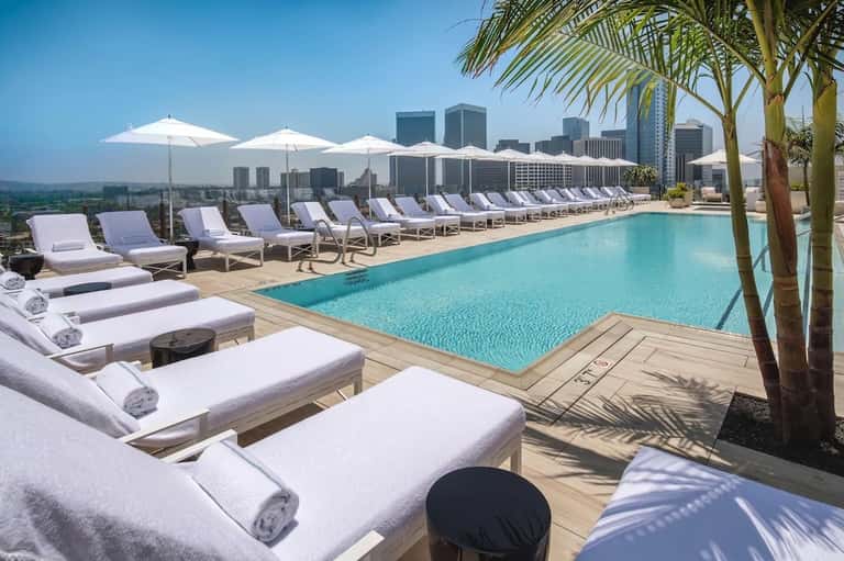 Luxury rooftop pool overlooking city skyline with white lounge chairs and umbrellas