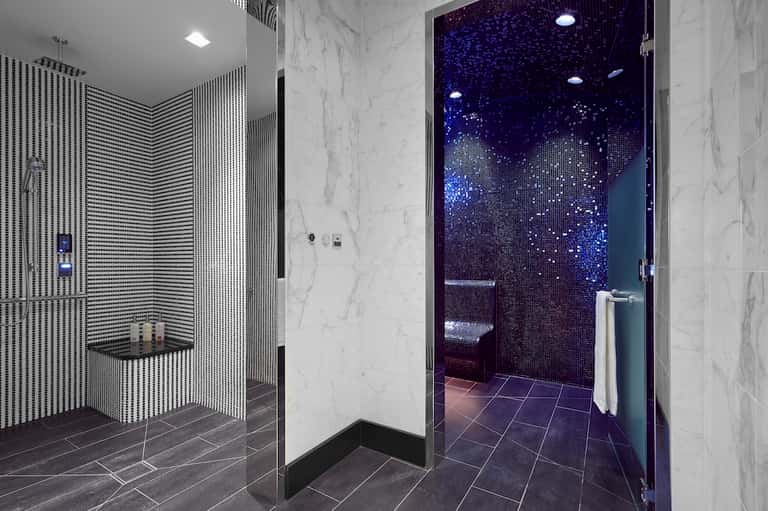 Modern hotel bathroom with marble walls, rainfall shower, and blue mosaic tiles