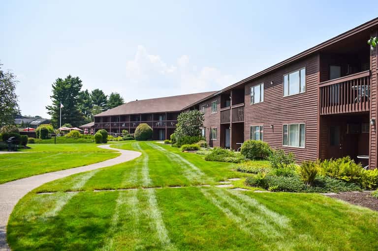 Resort exterior showing brown wooden buildings with manicured lawns and landscaped grounds