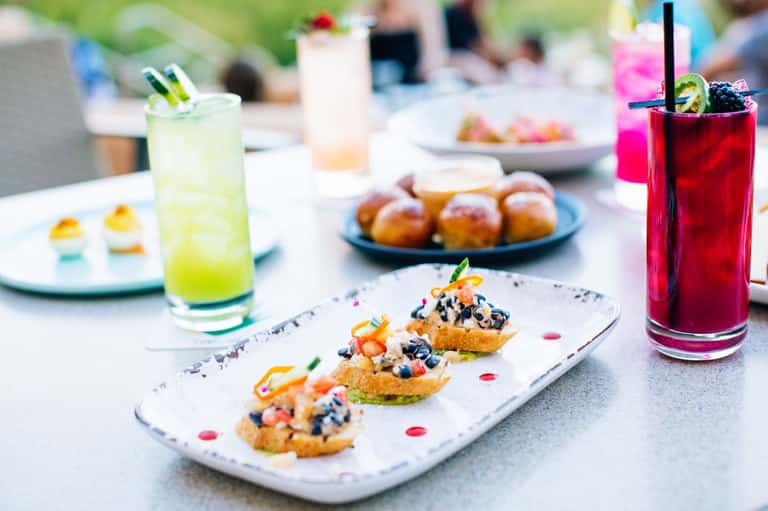 Outdoor dining table with gourmet appetizers and colorful cocktails at a resort gathering