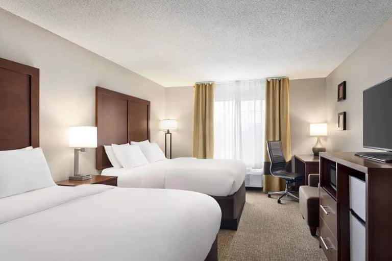 Hotel guest room with two queen beds, neutral tones, and modern furnishings