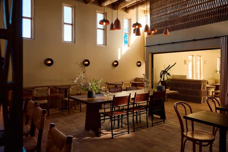 Rustic lounge with high ceilings, pendant lighting, wooden furniture, and glass doors