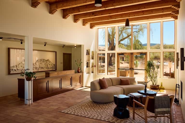 Spa reception area with modern curved furniture, natural wood beams, fireplace, and scenic outdoor views