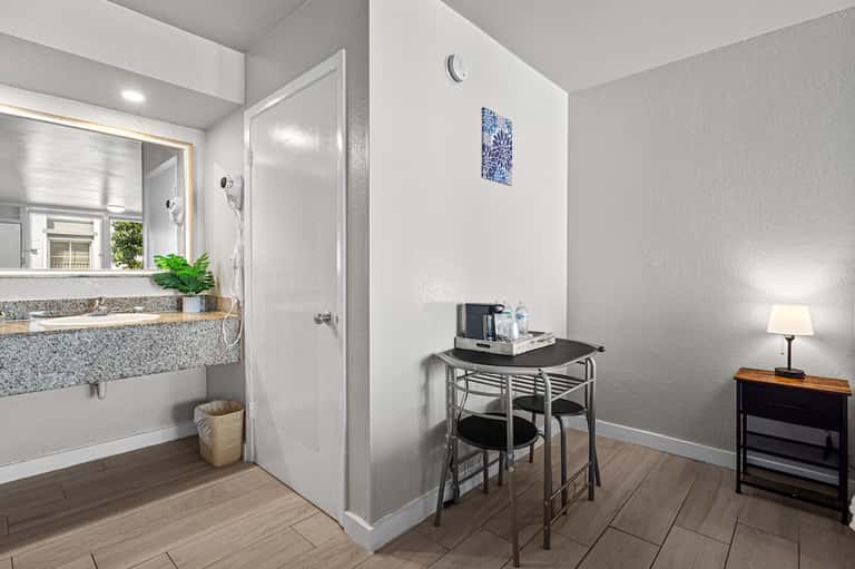 Hotel guest room bathroom with sink, shower, desk area, and hardwood flooring