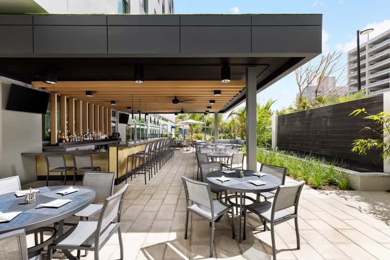 Modern outdoor terrace bar and restaurant with covered seating, wood accents, and landscaping