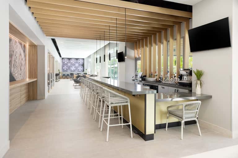 Modern hotel bar and lounge with wooden slat ceiling, long counter, bar seating, and contemporary design