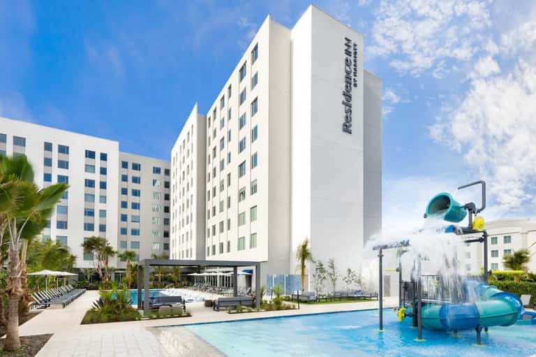 Resorts at Indigo Falls exterior with pool, water slide, palm trees, and multi-building resort complex
