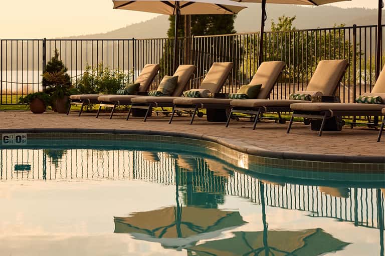 Mountain resort pool with lounge chairs, umbrellas, scenic valley views, and railing