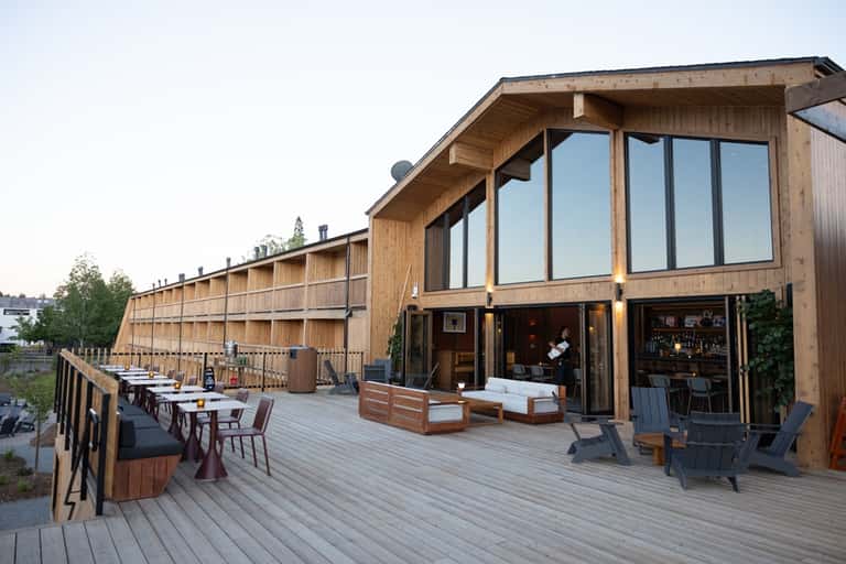 Contemporary wood lodge with deck, dining tables, lounge seating, and large windows