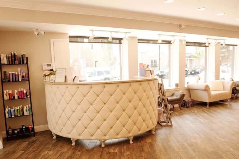 Spa reception area with cream quilted desk, product displays, and lounge seating