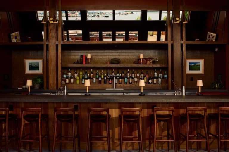 Upscale wooden bar with illuminated shelves of liquor bottles and seating