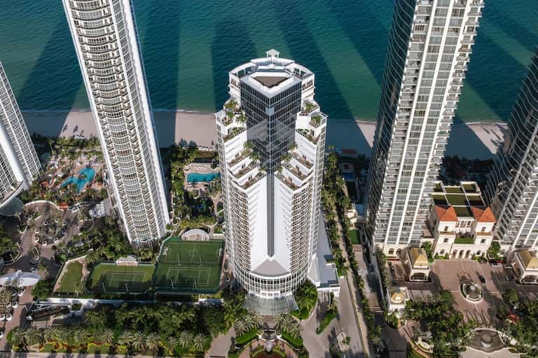 Beachfront residential towers with rooftop amenities and turquoise ocean views from above