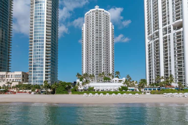 Beachfront high-rise hotel building with palm trees and sandy beach