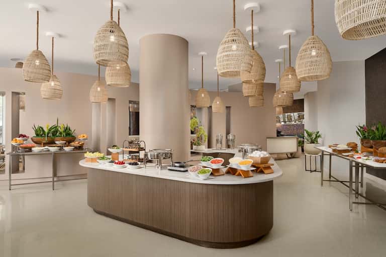 Contemporary dining area with woven hanging lamps, buffet bar, and fresh cuisine