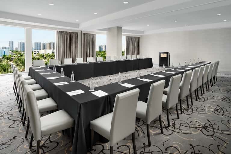 Conference room with long black tables, white chairs, and city views