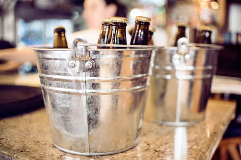 Metal ice buckets filled with beer bottles on a bar counter