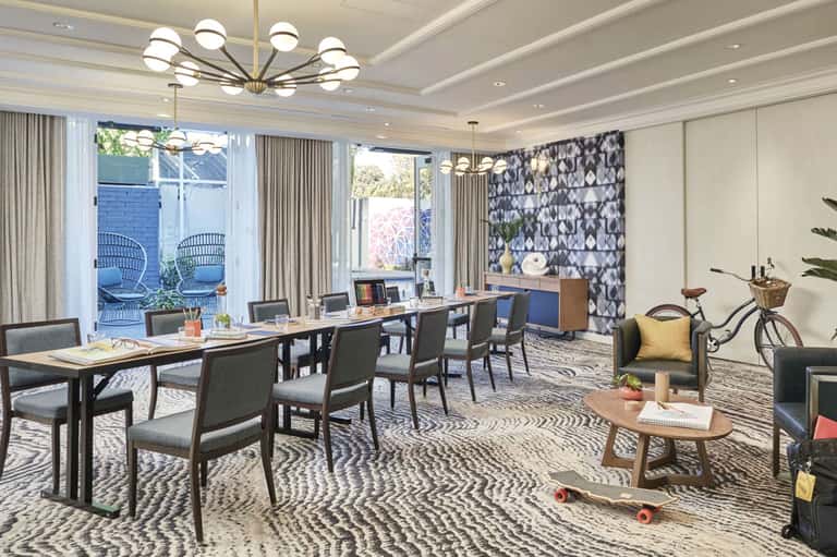 Modern office space with wooden desks, patterned accent wall, and outdoor patio access