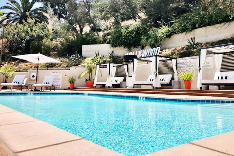 Resort pool with crystal blue water, white lounge chairs, cabanas, and surrounding tropical landscaping