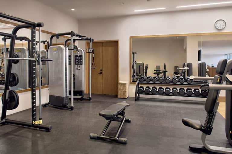 Modern fitness center with cardio machines, weights, dumbbells, and mirrored walls