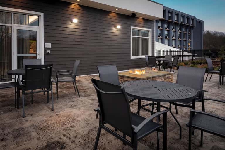 Outdoor patio with fire table, modern seating, and resort building backdrop
