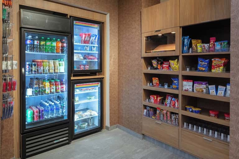 Hotel snack shop with beverage coolers and shelves stocked with snacks and beverages