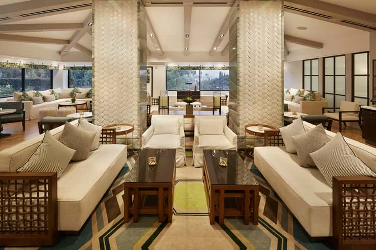 Elegant lounge with cream seating, herringbone columns, large windows, and contemporary design elements