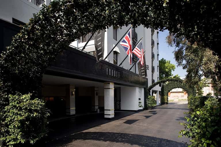 Historic hotel entrance with ivy-covered façade, British and American flags, columns, and ivy-lined courtyard