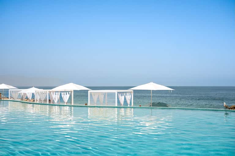 Infinity pool with white cabanas and ocean horizon blending seamlessly together