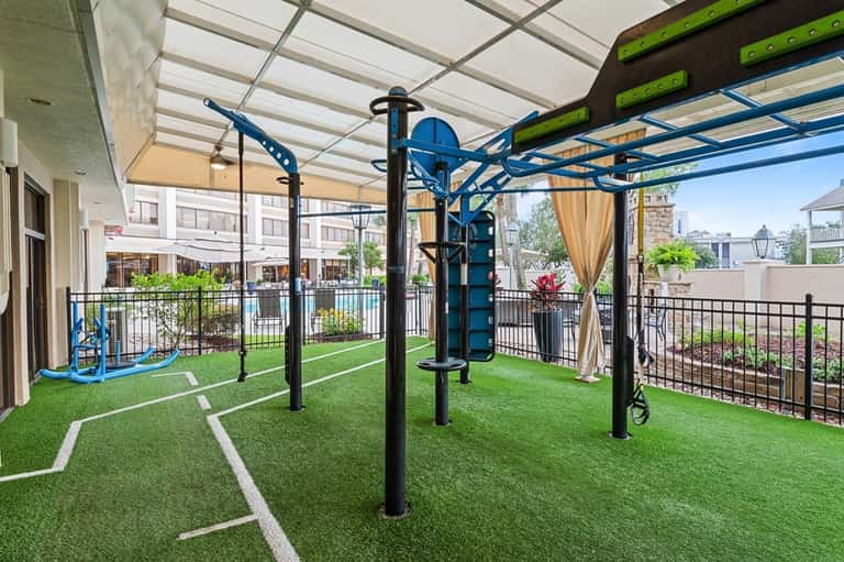 Rooftop fitness area with exercise equipment on synthetic turf under clear polycarbonate canopy