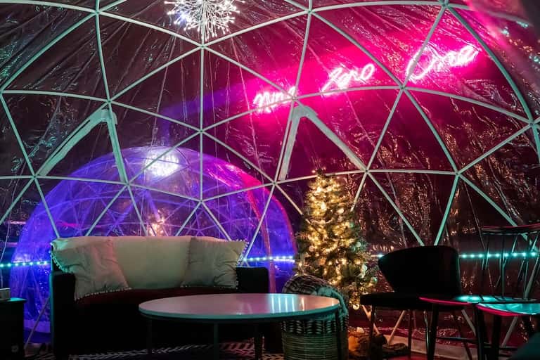 Illuminated geodesic dome interior with vibrant neon lighting and modern seating areas