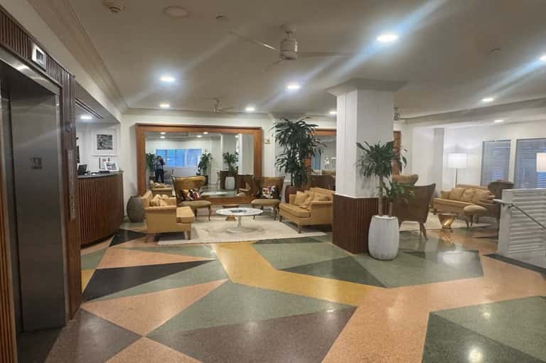 Spacious hotel lobby with geometric floor patterns, tan seating areas, and modern furnishings