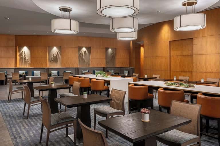 Elegant lounge with wood paneling, comfortable seating, pendant lights, and modern design