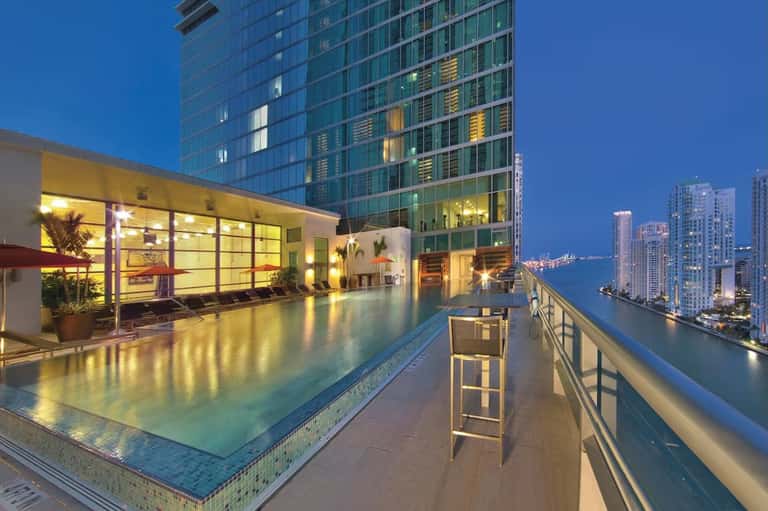 Rooftop infinity pool at night overlooking illuminated city skyline and waterfront