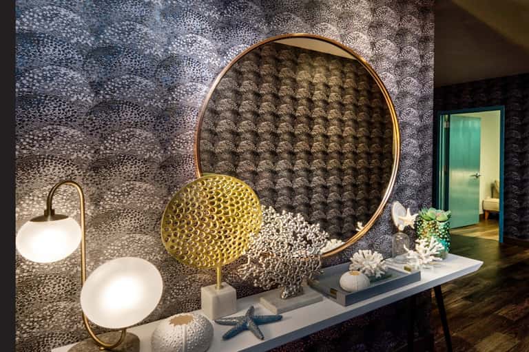 Luxury spa entrance with textured wall art, brass circular mirror, decorative objects, and ambient lighting