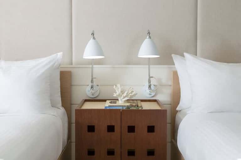 Twin beds with beige headboard, white pillows, and wooden nightstand