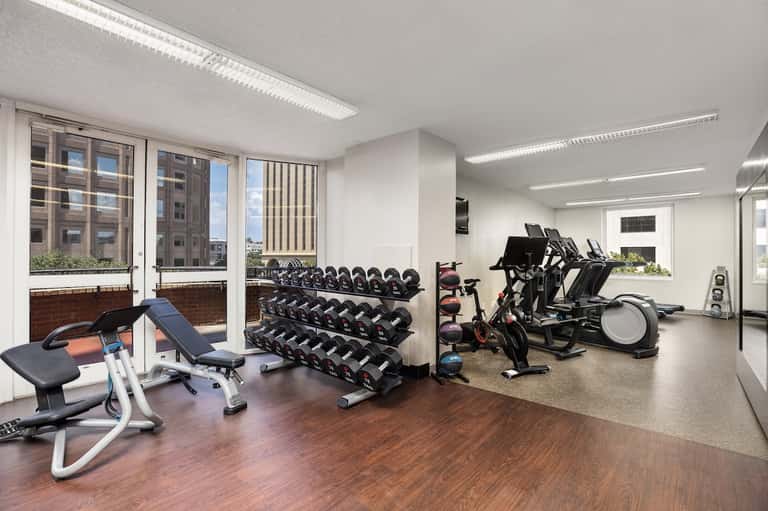 Modern fitness center with dumbbells, stationary bikes, exercise equipment, and city views