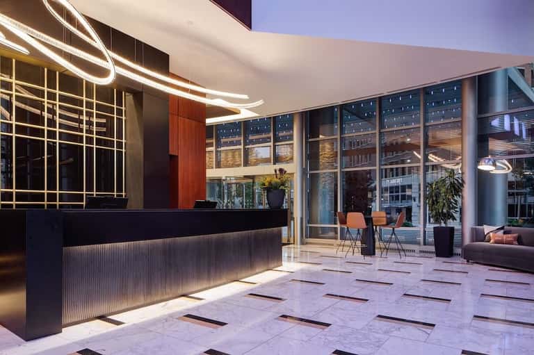 Modern hotel reception desk at dusk with curved lighting design, floor-to-ceiling windows, and contemporary furnishings