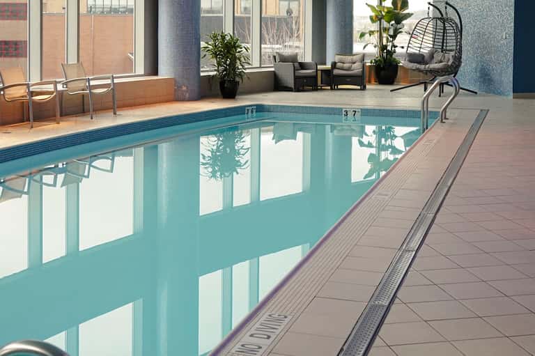 Indoor heated pool with lounge seating area, floor-to-ceiling windows, and modern amenities