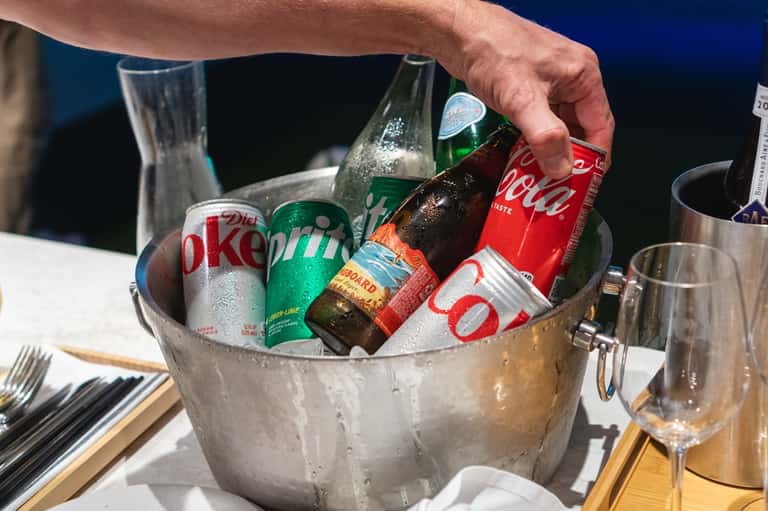 Ice bucket with chilled beverages and glasses on dining table at outdoor resort setting