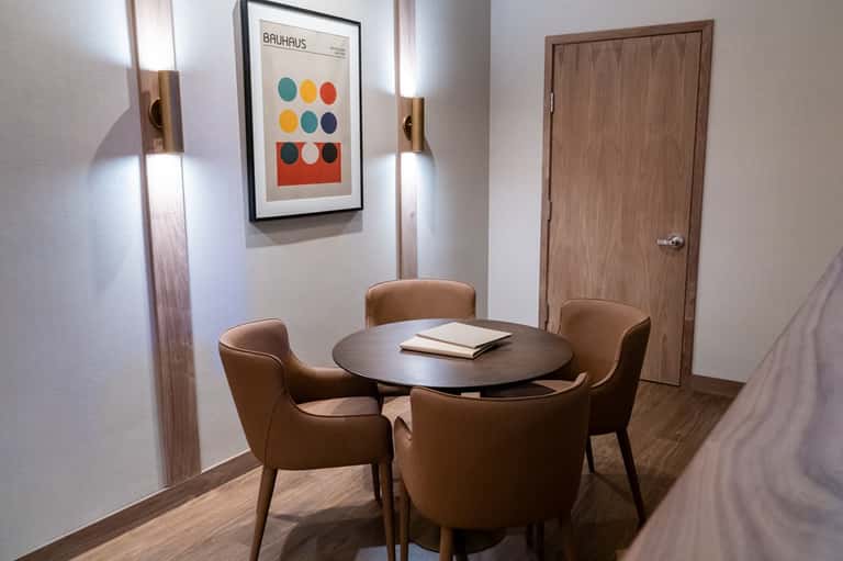 Small meeting room with round table, brown leather chairs, wood door, and Bauhaus artwork