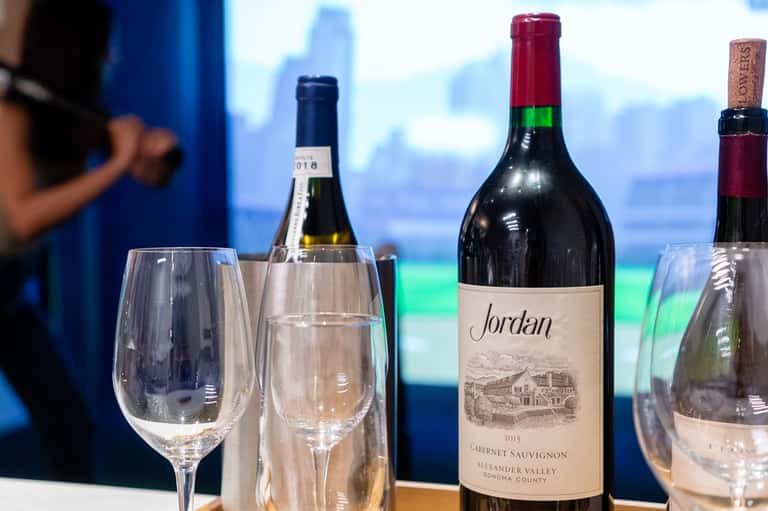 Wine bottles and glasses displayed on a table with ocean and sky view in the background