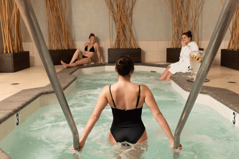 Guests enjoying thermal spa bath with natural mineral water, heated pool surrounded by lounge seating and comfort elements