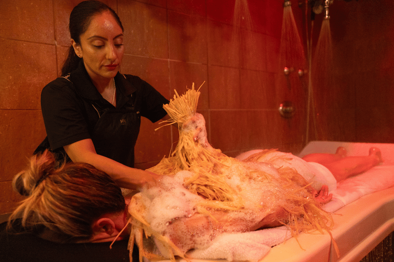 Spa therapist applying exfoliating treatment to guest