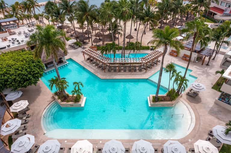 Aerial view of large resort pool complex with palm trees and cabanas