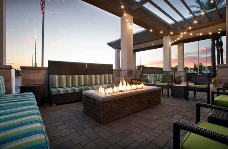 Resort rooftop terrace with fire pit, striped seating, string lights, and sunset view at dusk